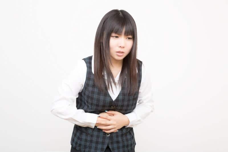 仕事のストレスで腹痛になる女性